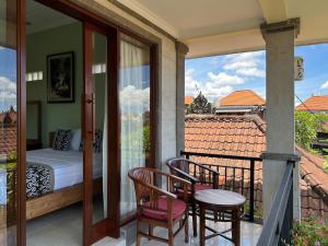 a balcony with a bedroom and a bed and two chairs at Sudiana House in Ubud