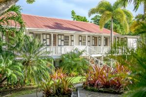 un bâtiment avec un toit rouge et des palmiers dans l'établissement Montpelier Plantation & Beach, à Nevis
