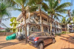 a car parked in front of a house with palm trees at Oceanside Beach House-By Roseal in Baga