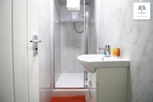 a white bathroom with a sink and a shower at Modern 2 Bed Apartment - Near City Centre - By EKLIVING LUXE in Cardiff