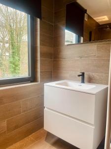 een badkamer met een witte wastafel en een spiegel bij Le Quatre F in La-Roche-en-Ardenne