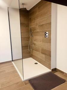 a shower with a glass door and wooden wall at Le Quatre F in La Roche-en-Ardenne