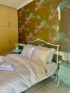 a bedroom with a bed with a floral wall at CYNTHIA COMFORT LIVING VOLOS in Volos
