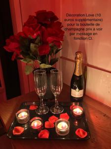 - un plateau avec des bougies, une bouteille de vin et des roses dans l'établissement Dépendance privative et indépendante Le Cocon, à Montgeron