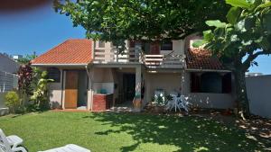 a house with a yard with white chairs and a tree at Casa de veraneio Lar doce mar in Capão da Canoa