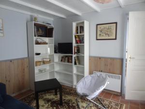 een woonkamer met witte boekenplanken en een stoel bij Les Ecuries du Préchard in La Chapelle-Chaussée