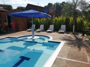 uma piscina com um guarda-sol azul e cadeiras em Finca la sharola em Guaduala