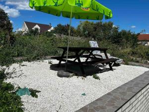 a picnic table with a green umbrella and a bench at Lumineux Appart à Disneyland in Montry