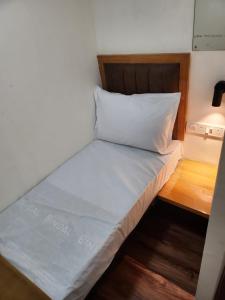 a bed in a small room with a white pillow at Galaxy Cabin Stay And Dormitory in Mumbai