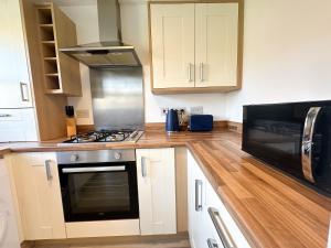 a kitchen with a stove and a microwave at Coral House by Blue Skies Stays in Thornaby on Tees