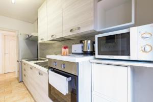 uma cozinha com armários brancos e um micro-ondas em Amedeo Comfort Apartment at Chiaia by Napoliapartments em Nápoles