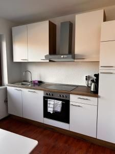 a kitchen with white cabinets and a stove top oven at Hotel Rennekamp in Oyten