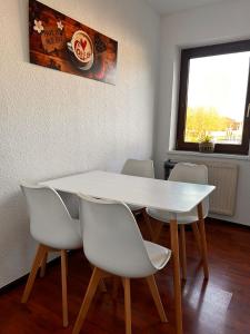 una mesa y sillas blancas en una habitación con ventana en Hotel Rennekamp, en Oyten