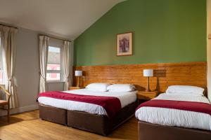 two beds in a room with green walls at The Oystercatcher Lodge Guest House in Carlingford