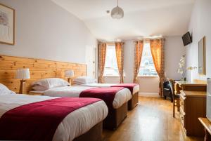 Habitación de hotel con 3 camas y mantas rojas en The Oystercatcher Lodge Guest House en Carlingford