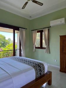 a bedroom with a bed and a balcony with windows at Sudiana House in Ubud