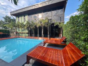 una piscina con 2 bancos junto a un edificio en โค้งโดนัท พรีเมียม พูลวิลล่า en U Thong