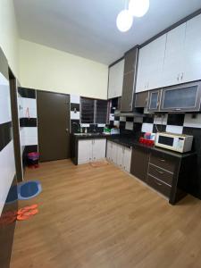 a kitchen with black and white cabinets and a wooden floor at Frosty Hills Homestay in Tanah Rata
