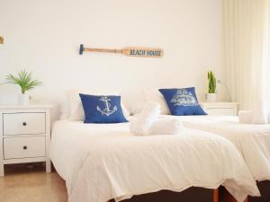 2 Betten mit weißen und blauen Kissen in einem Zimmer in der Unterkunft Luminoso apartamento de 3 dormitorios a pie de playa en Torremolinos in Torremolinos