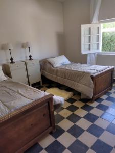 een slaapkamer met 2 bedden en een geruite vloer bij Casa La Cumbre in La Cumbre