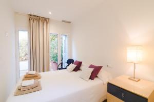 シッチェスにあるSitges Suites Bのベッドと窓のある白い寝室