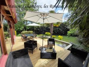 胡伊的住宿－Domaine de l'Ermitage，木制甲板配有桌椅和遮阳伞