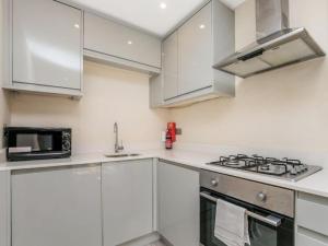 uma cozinha branca com um fogão e um micro-ondas em Pass the Keys Ealing Queen of the Suburbs 2BD Apartment em Londres