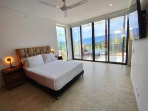a bedroom with a large bed and large windows at Mountain View Anapoima in Anapoima