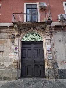 einen Eingang zu einem Gebäude mit einer schwarzen Tür und einem Balkon in der Unterkunft Le Volte And Suite in Catania