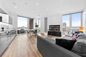 uma sala de estar com um sofá cinzento e uma cozinha em Battersea Penthouse Sleep 9 WH em Londres