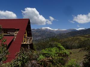 een huis met een rood dak en bergen op de achtergrond bij La Teja Experience in Güicán