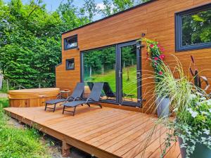 uma casa com um deque com duas cadeiras e uma mesa em La mini maison dans la prairie em Libin