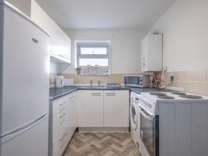 a white kitchen with a stove and a refrigerator at Cosy Coastal Apartment in Whitley Bay