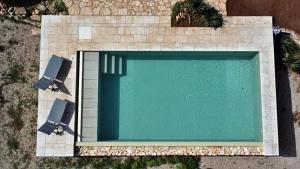 einen Blick über einen Pool mit 2 Stühlen in der Unterkunft Villa Archidea - Con Piscina Privata Ed Ampio Giardino in Specchia