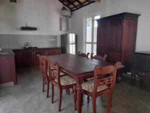 a kitchen with a wooden table and wooden chairs at Villa one in Balapitiya