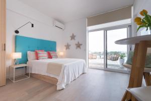 a white bedroom with a bed and a large window at Ran de Mar - First Line Studio in Alcudia