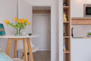 a kitchen with a table and a vase of yellow flowers at Ran de Mar - First Line Studio in Alcudia