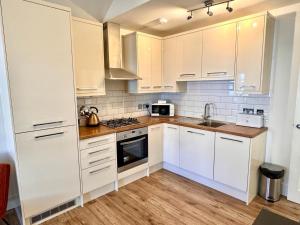 a kitchen with white cabinets and a sink at Cosy town centre apartment in Bedford