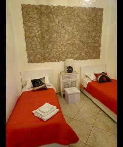 two beds in a room with red sheets at Residenza Giuseppina in Siracusa