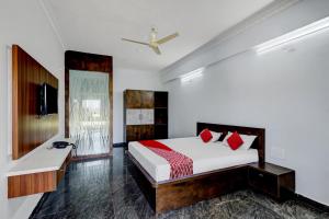 1 dormitorio con 1 cama con almohadas rojas en OYO JDR GARDENS, en Tirupati