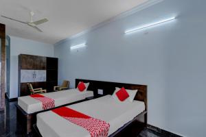 2 camas con almohadas rojas en una habitación en OYO JDR GARDENS, en Tirupati