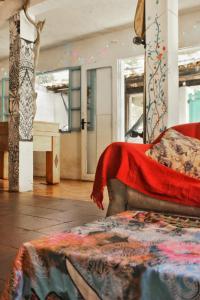 um quarto com uma cama com um cobertor vermelho em Raizes Surf and Bar Hostel em Búzios