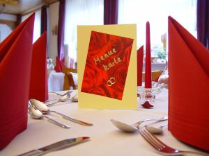 - une table avec des serviettes rouges et des ustensiles en argent dans l'établissement Gasthaus Debelius Beltershausen, à Marbourg