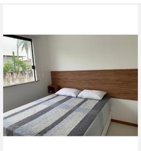 a bedroom with a large bed with a wooden headboard at Solaris Village Imbassaí in Imbassai