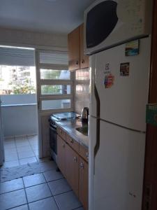 a kitchen with a white refrigerator and a stove at Edificio Daniela Ap 101 in Bombinhas
