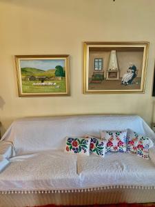 a white couch in a room with two pictures on the wall at Lake Stories in Koutsodímos
