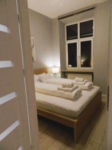 a bedroom with a bed with white sheets and a window at Apartament Donnka in Krakow