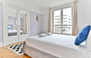 een witte slaapkamer met een groot bed met een blauw kussen bij Appartement luxueux Porte Maillot - Neuilly -II in Neuilly-sur-Seine