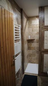 uma casa de banho com um chuveiro e uma porta de madeira em Gîte Aliénor en Anjou em Vernoil