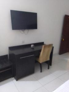uma secretária preta com uma cadeira e uma televisão na parede em St Theresers apartments lodge4 em Lagos